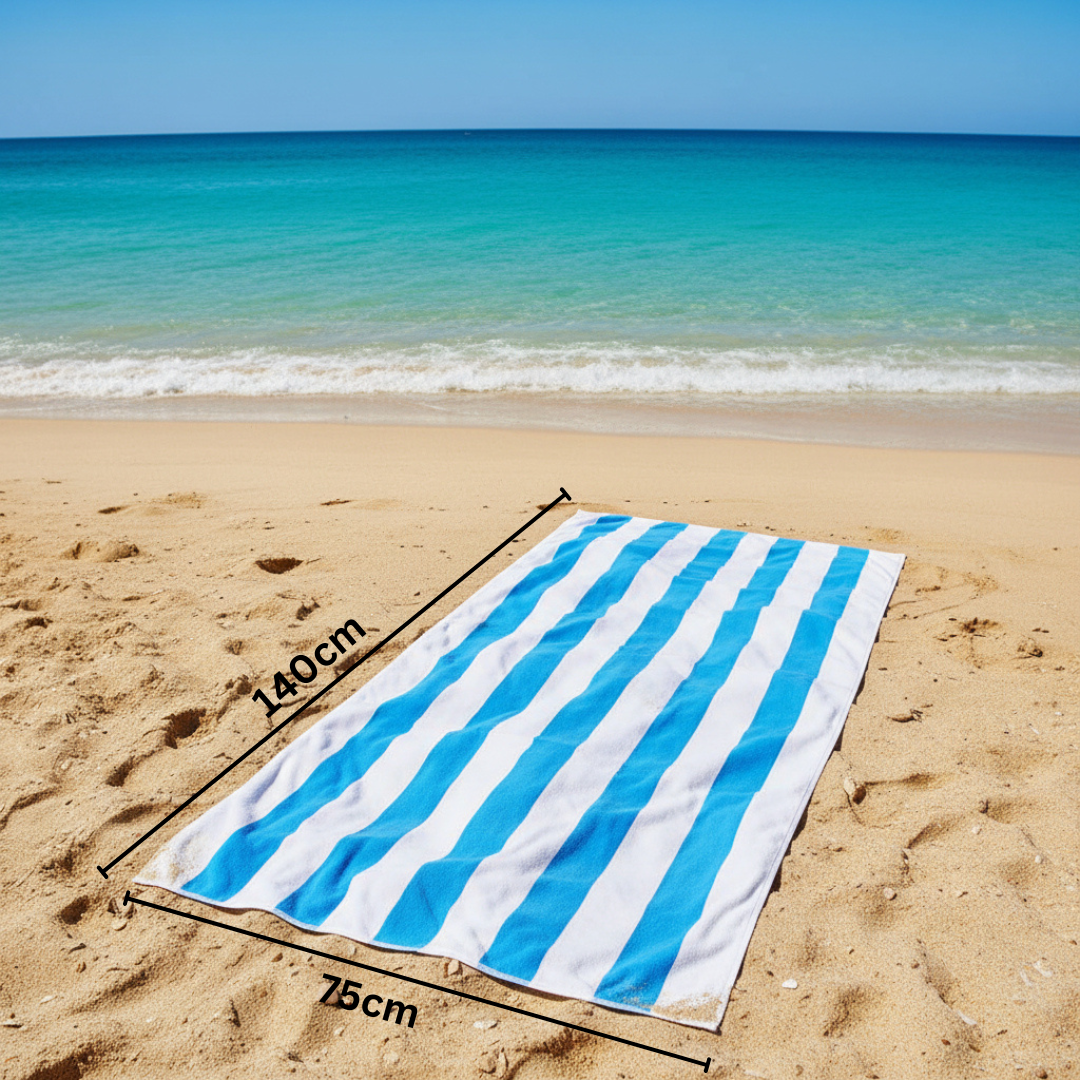 Blue and white striped towel on a sandy beach with ocean view