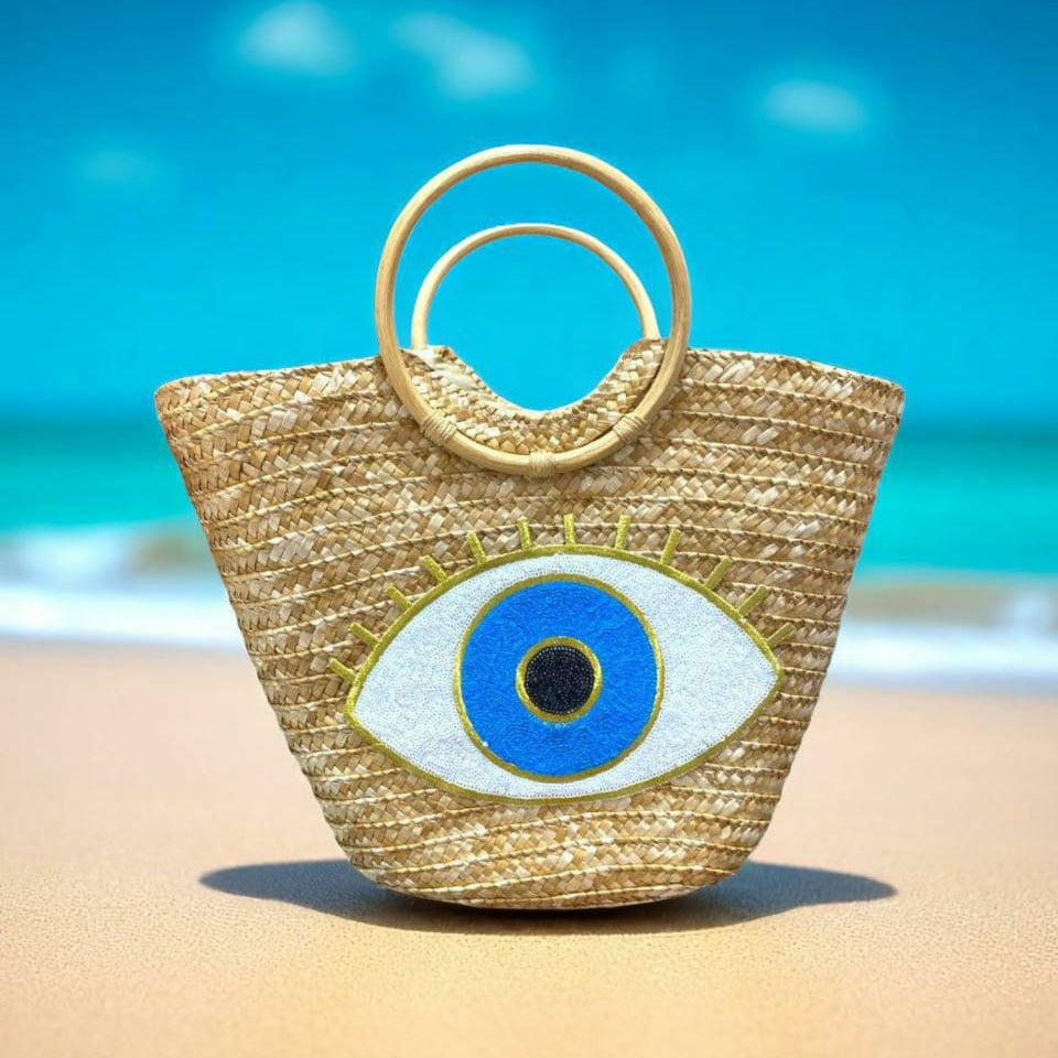 Woven straw bag with eye design on a beach
