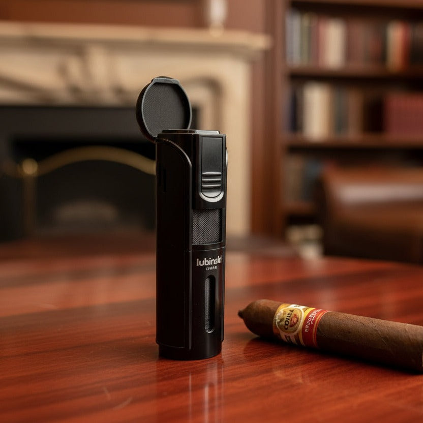 Black lighter with branding on a wooden surface next to a cigar, with a blurred background of books and furniture