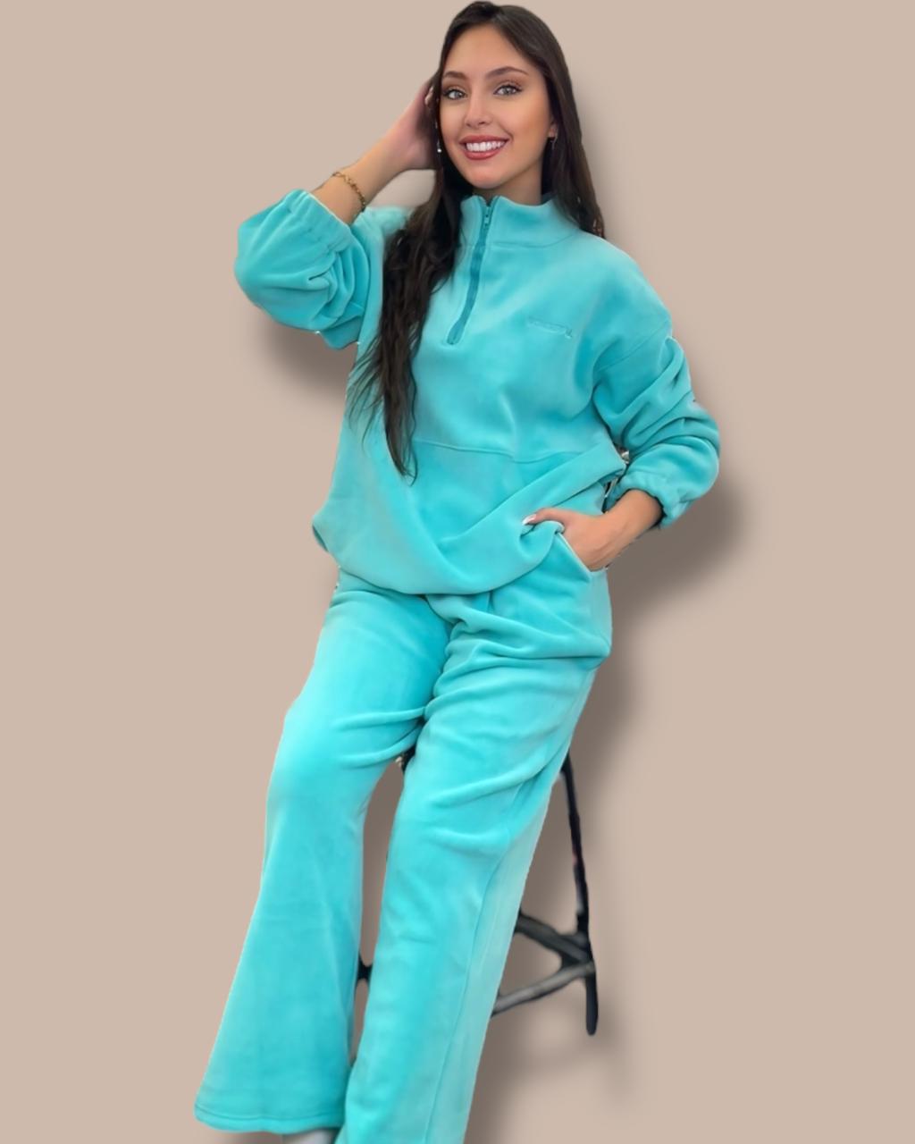 Woman wearing an aqua outfit against a beige background