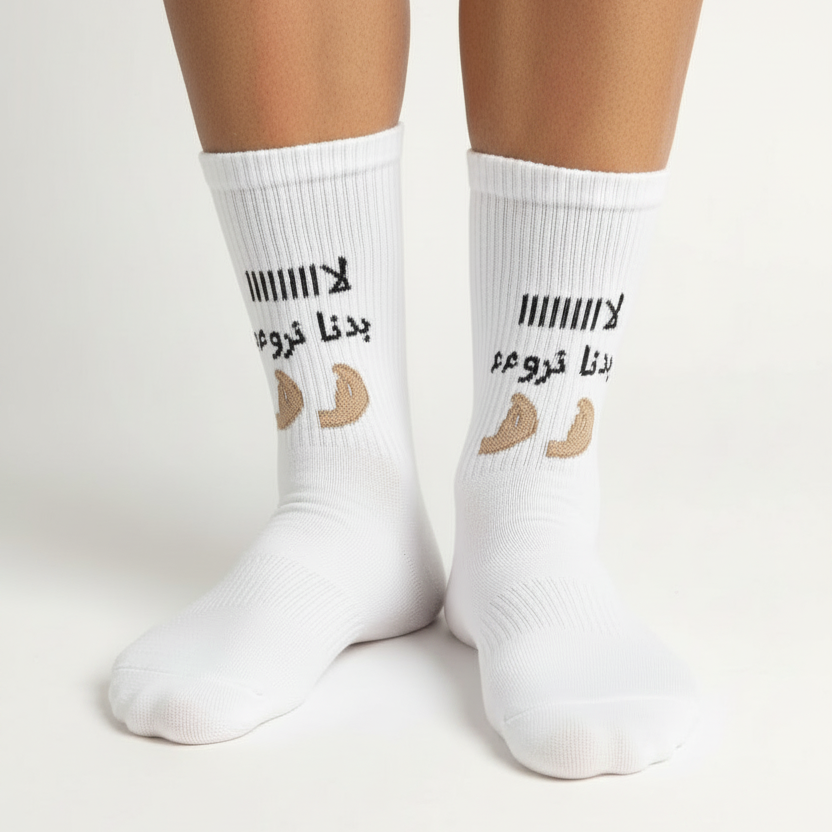 Pair of white ribbed socks worn on both feet showing the Arabic slogan design