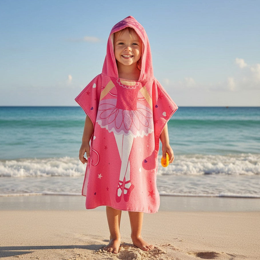 Child wearing a pink ballerina hooded towel on a beach with ocean in the background
