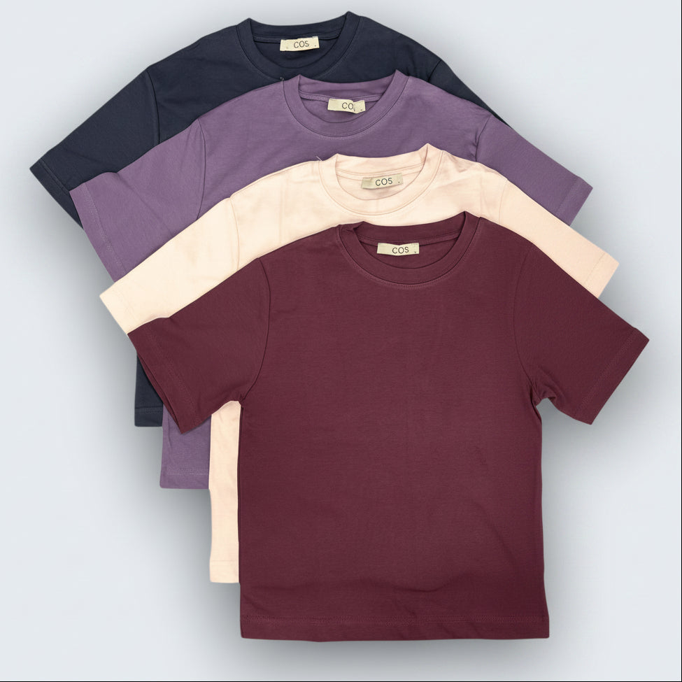 Four tshirts in black, purple, beige, and maroon on a light gray background