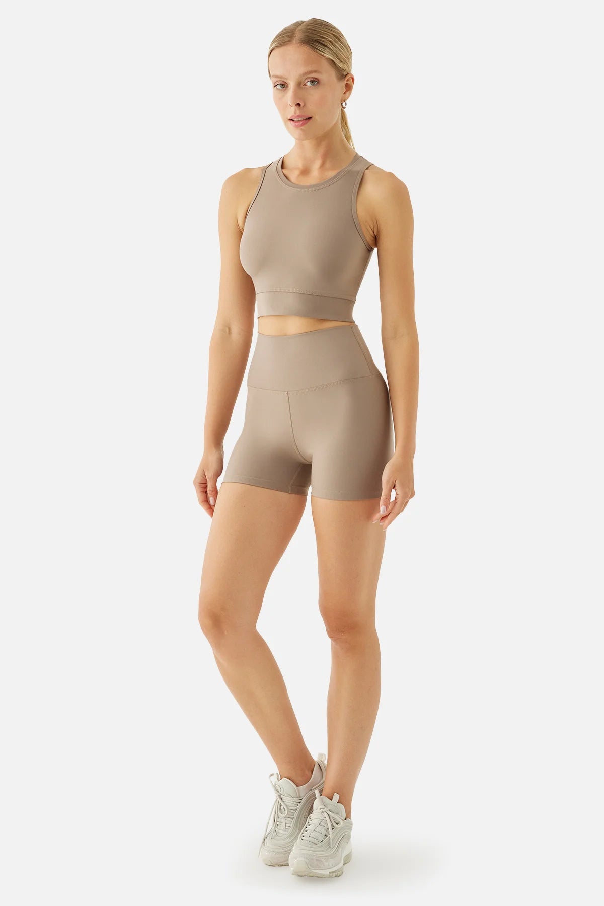 Woman wearing a beige athletic outfit on a white background
