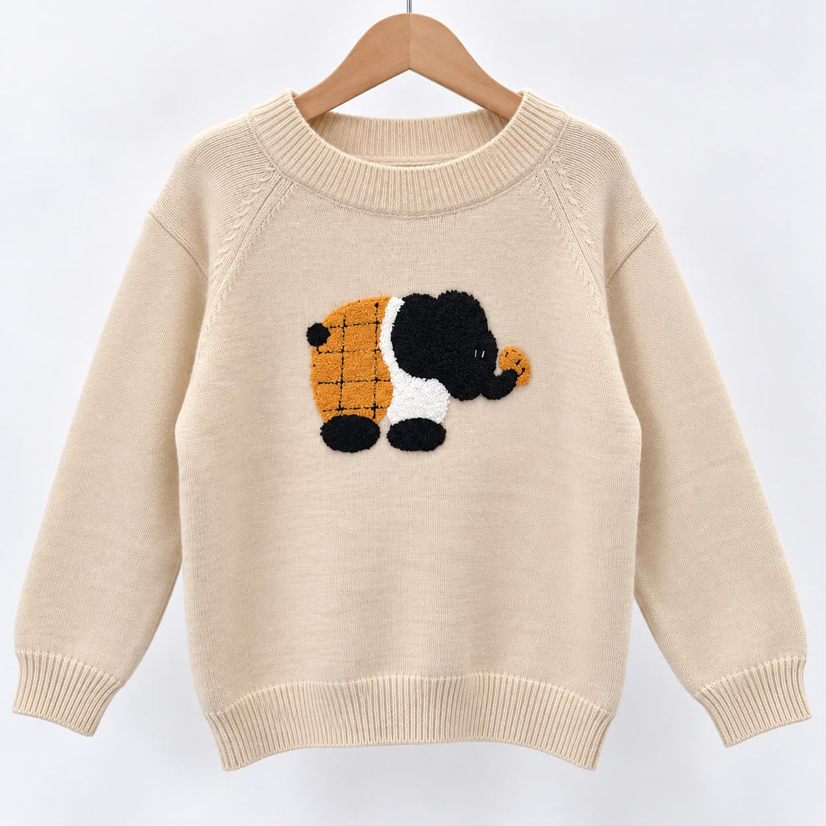 Beige knit sweater on a hanger with a fuzzy elephant patch in black, white and orange