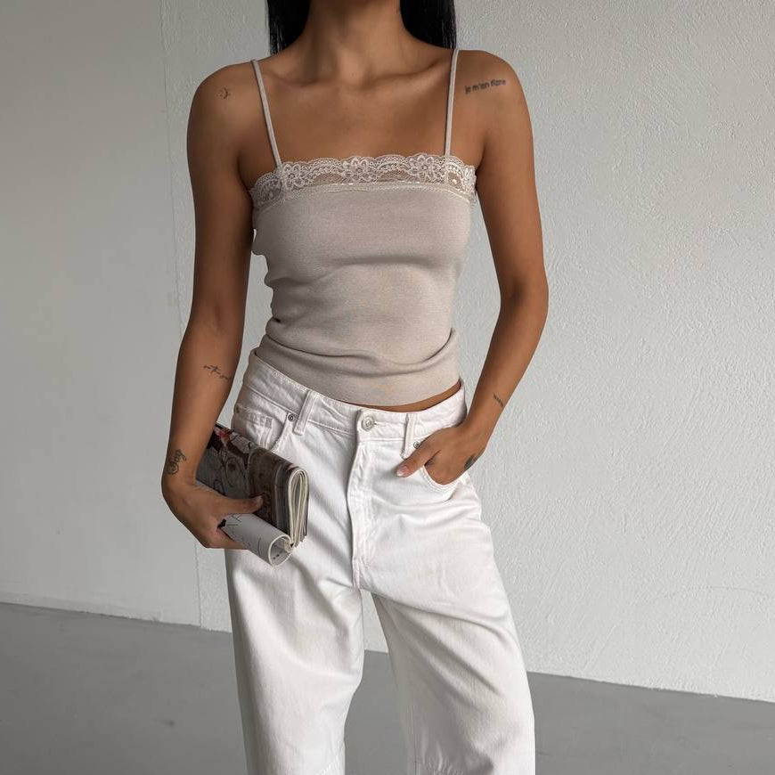 Person wearing a beige top and white jeans against a plain background