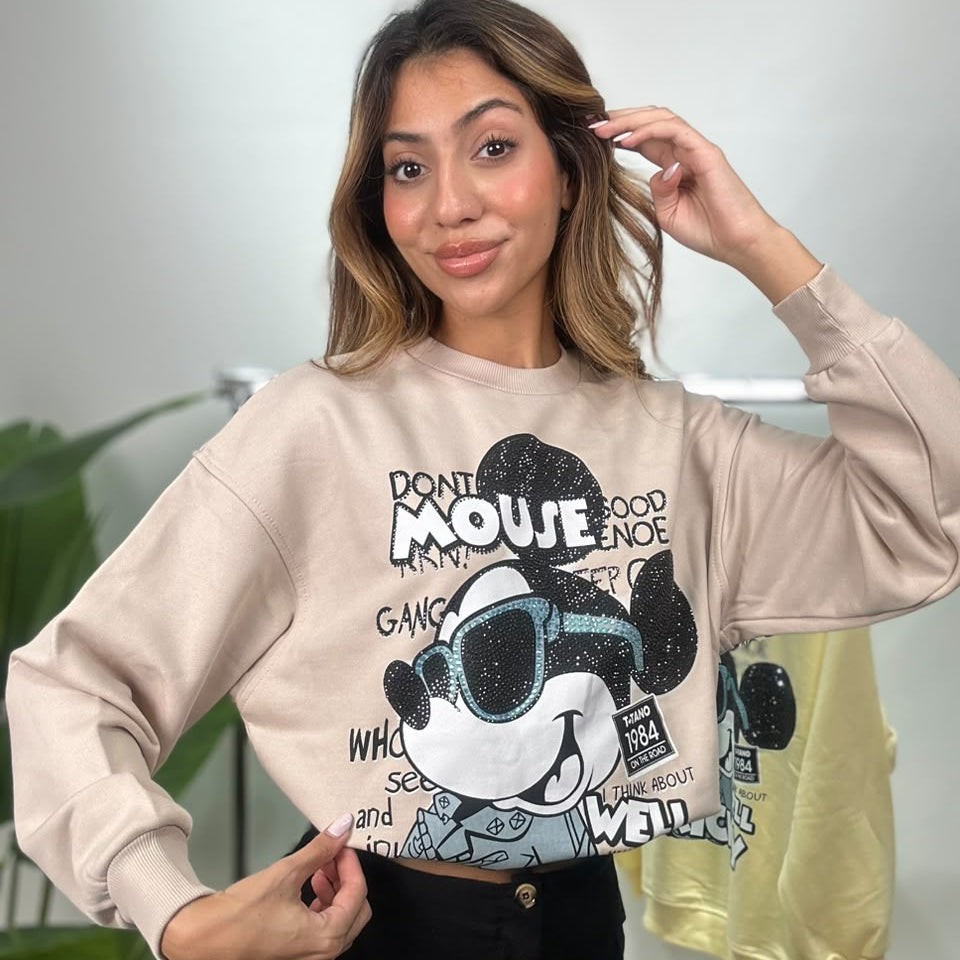 Woman in a beige Mickey Mouse sweatshirt with black rhinestones and blue rhinestone sunglasses