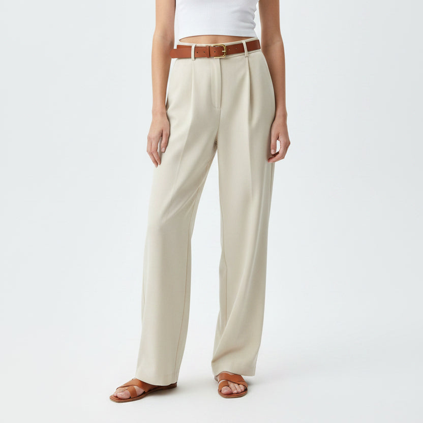 Person wearing beige wide-leg pants with a brown belt on a white background