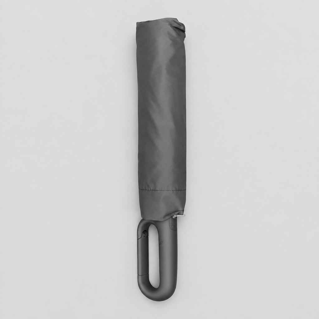 Folded charcoal black compact umbrella with a looped hook handle on a light grey background