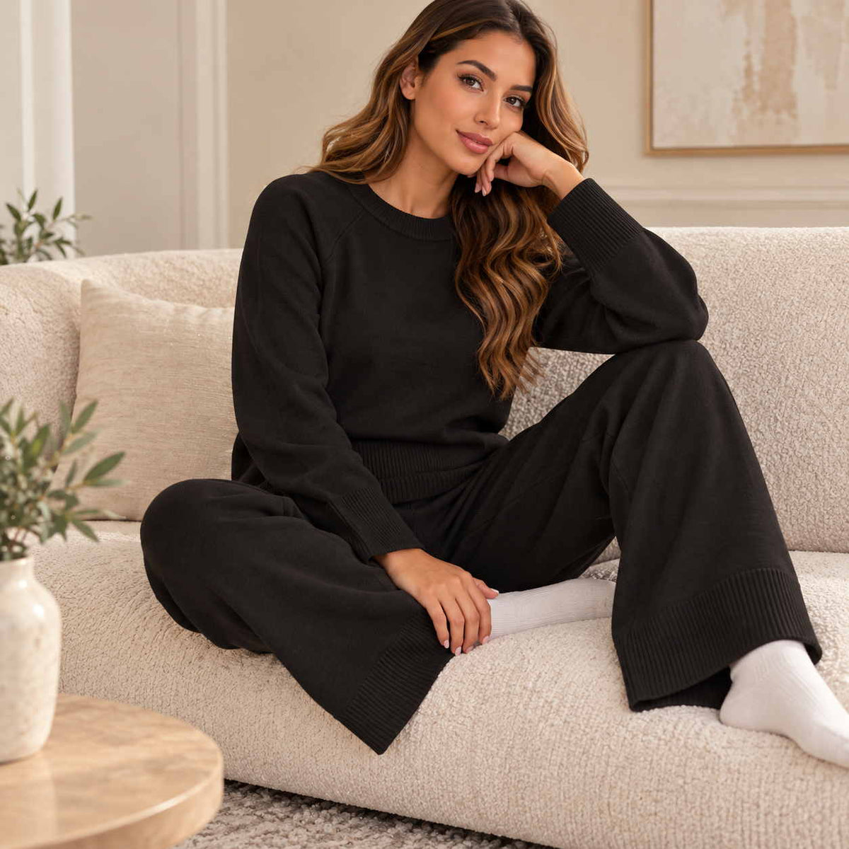 Black knit crew neck jumper and wide leg pants set, worn curled up on a cream sofa