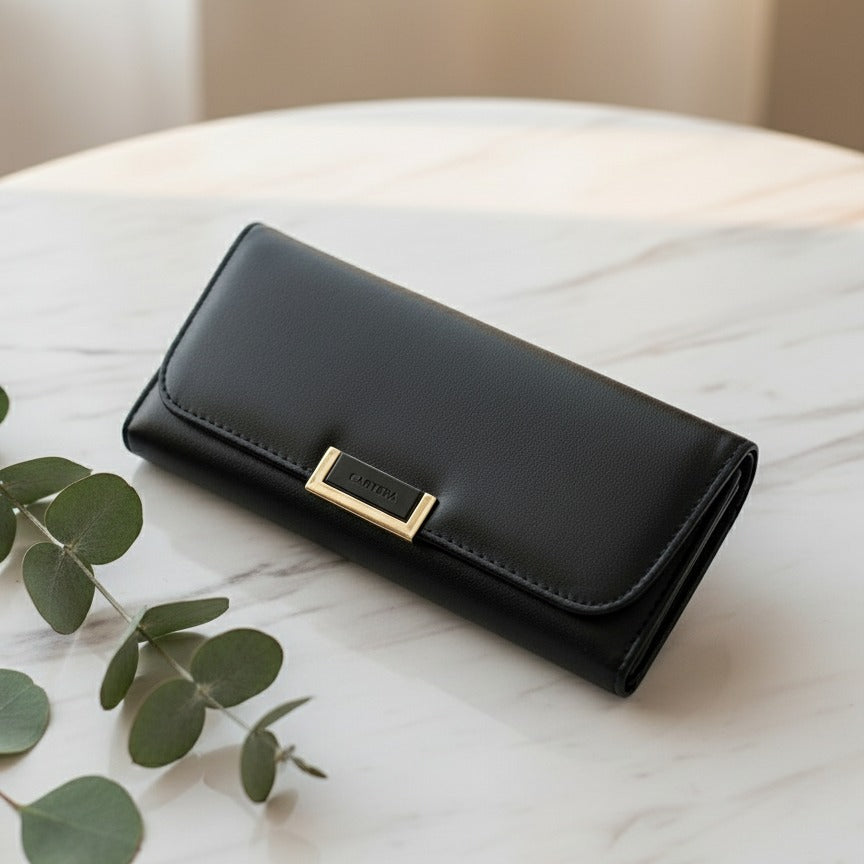 Black wallet with a gold clasp on a marble surface with leaves