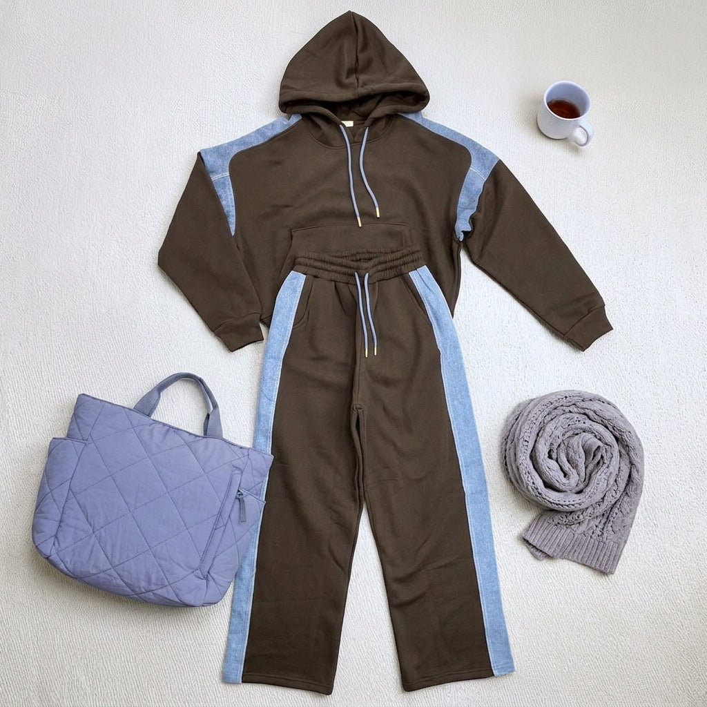 Black hoodie and wide leg pants with light blue stripes laid flat beside a quilted tote
