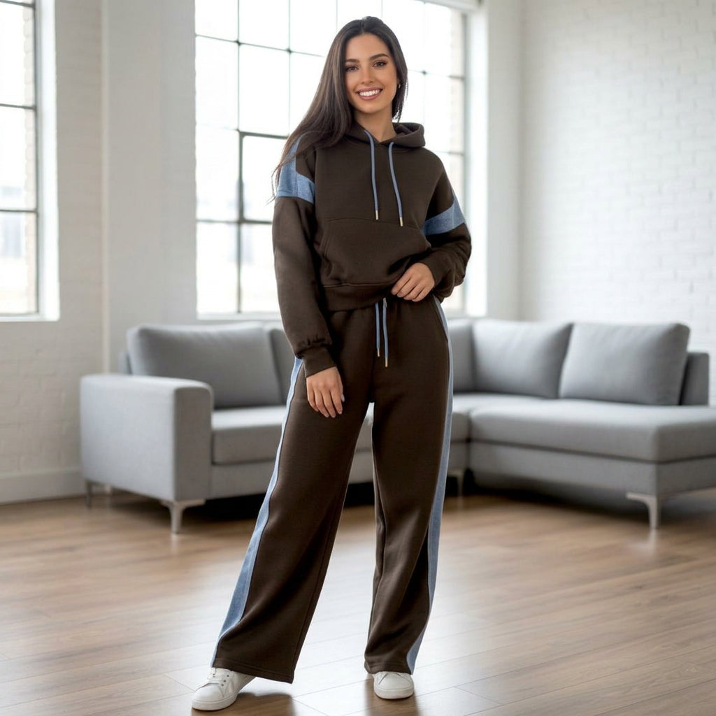 Woman in a black hooded jogging set with light blue side stripes in a modern living room