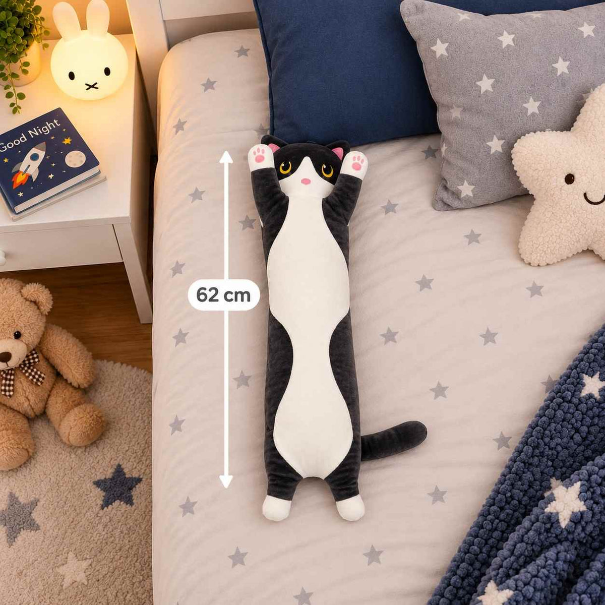 Black and white long cat body pillow plush on a star print bed beside a 62 cm measuring line