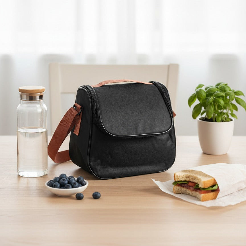 Black bag on a table with a water bottle, bowl of blueberries, and sandwich