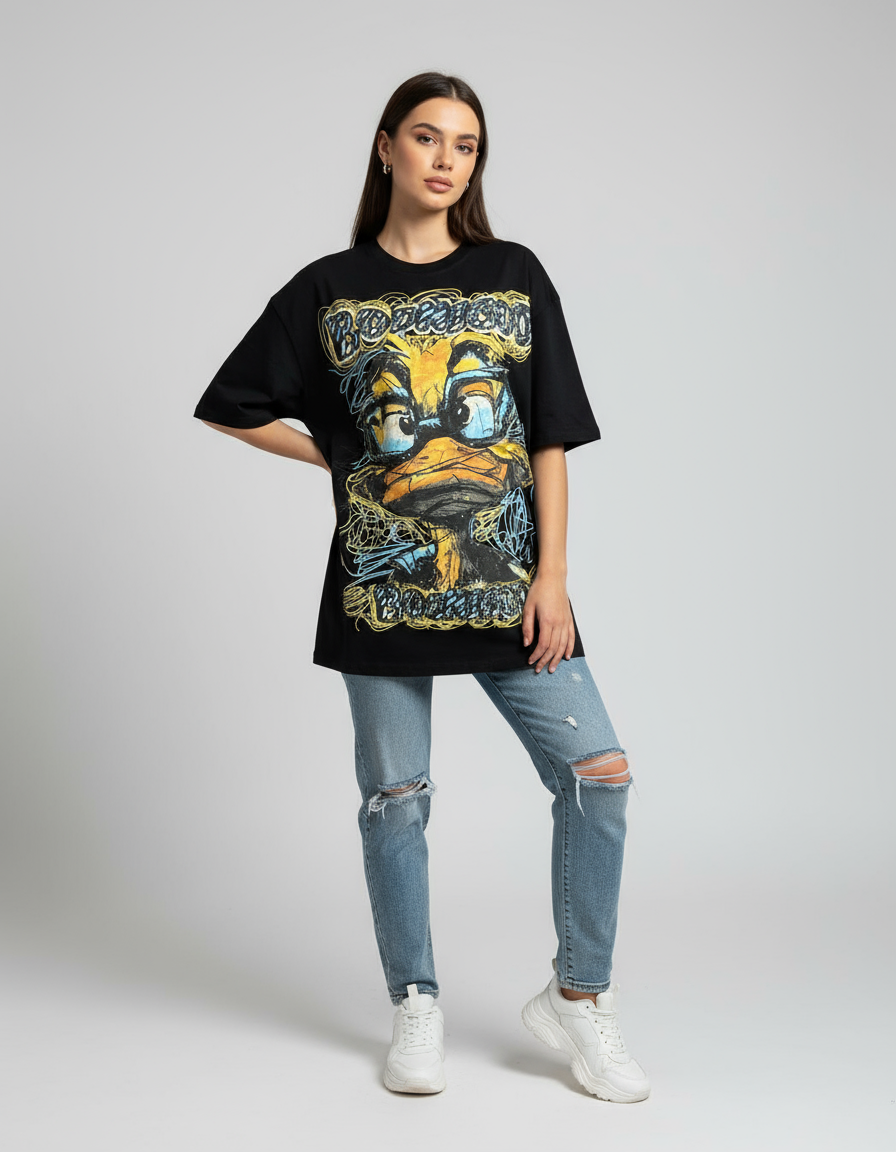 Person wearing a black graphic tshirt with a yellow duck graphic and ripped jeans on a plain background