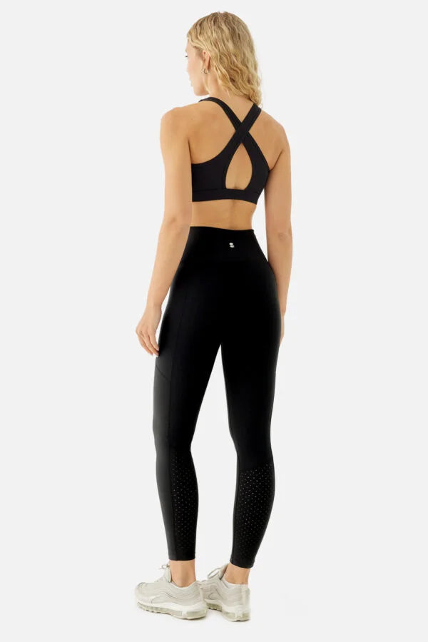 Person wearing black athletic leggings and sports bra on a white background