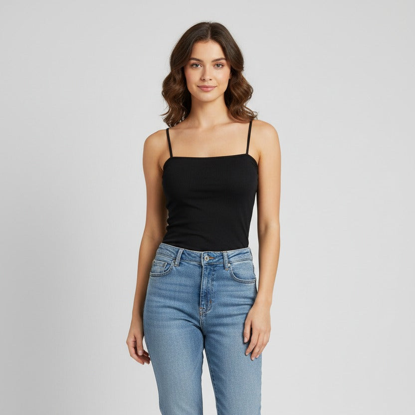 Woman wearing a black tank top and light blue jeans on a gray background