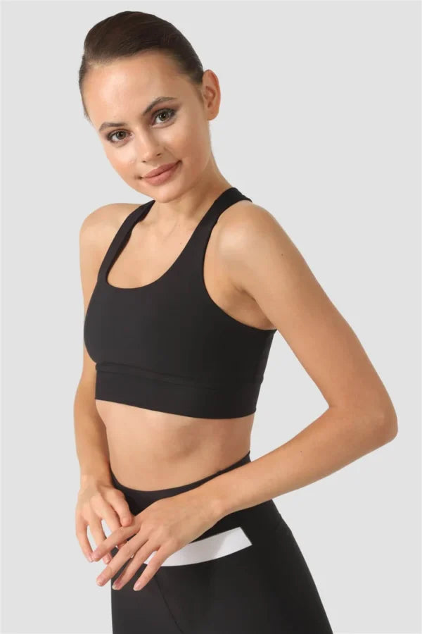 Woman wearing a black sports bra and leggings on a light grey background