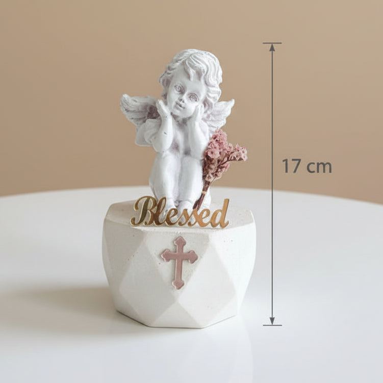 Seated cherub resting its chin on both hands next to pink dried gypsophila, 17 cm