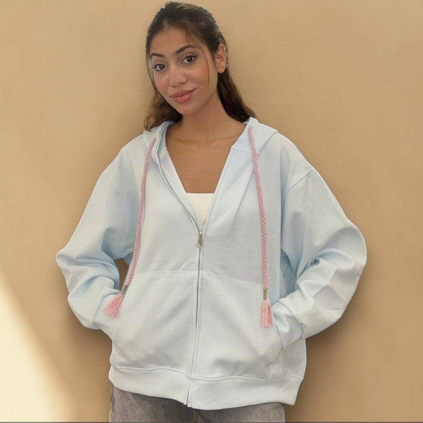 Baby blue hoodie zipped to the chin against a warm tan backdrop