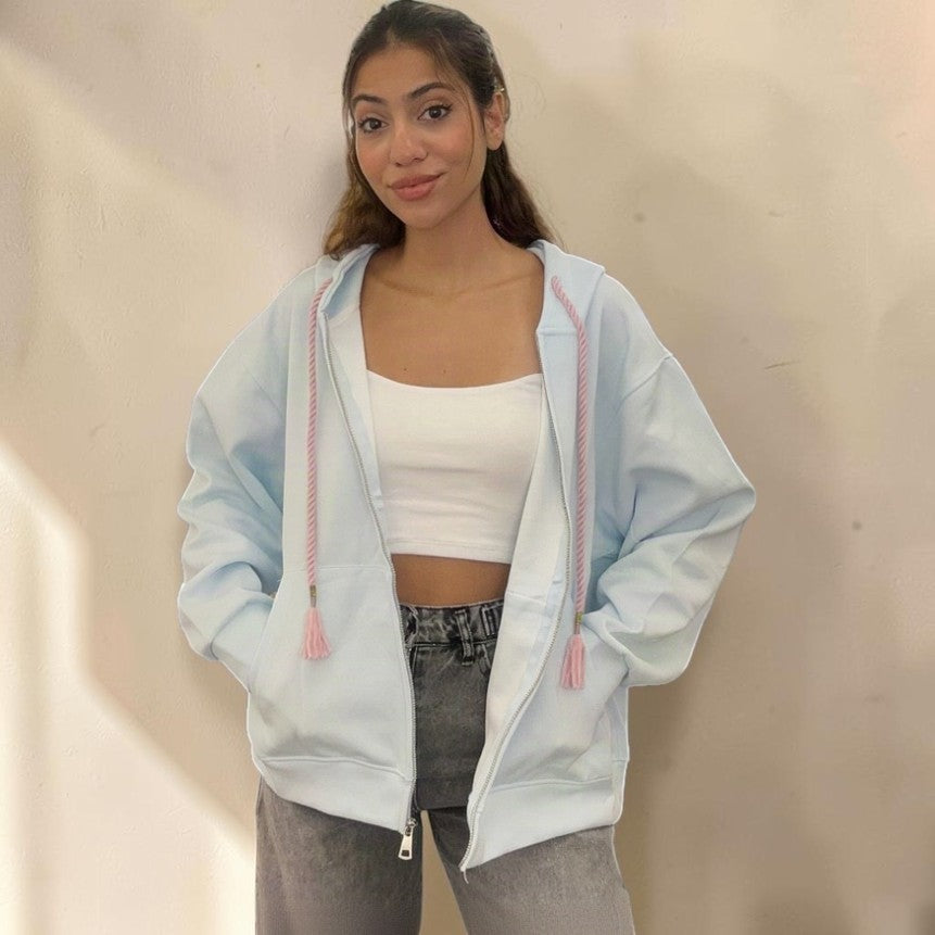 Pale blue oversized zip hoodie jacket worn open with pink tassel drawstrings