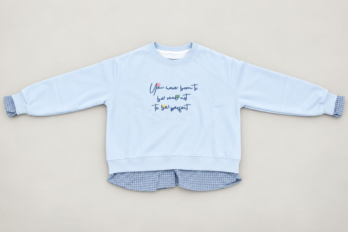Powder blue sweatshirt flat lay showing the gingham shirt tail and frilled cuffs