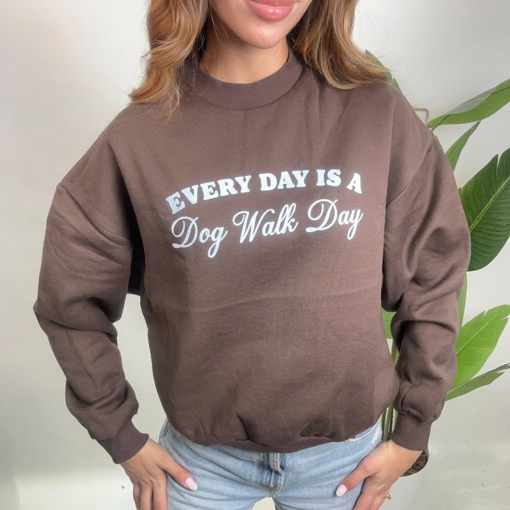 Close up of a brown sweatshirt with a white Every Day Is A Dog Walk Day print and ribbed cuffs