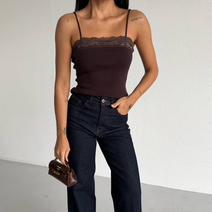 Woman wearing a brown top and dark blue jeans against a white background
