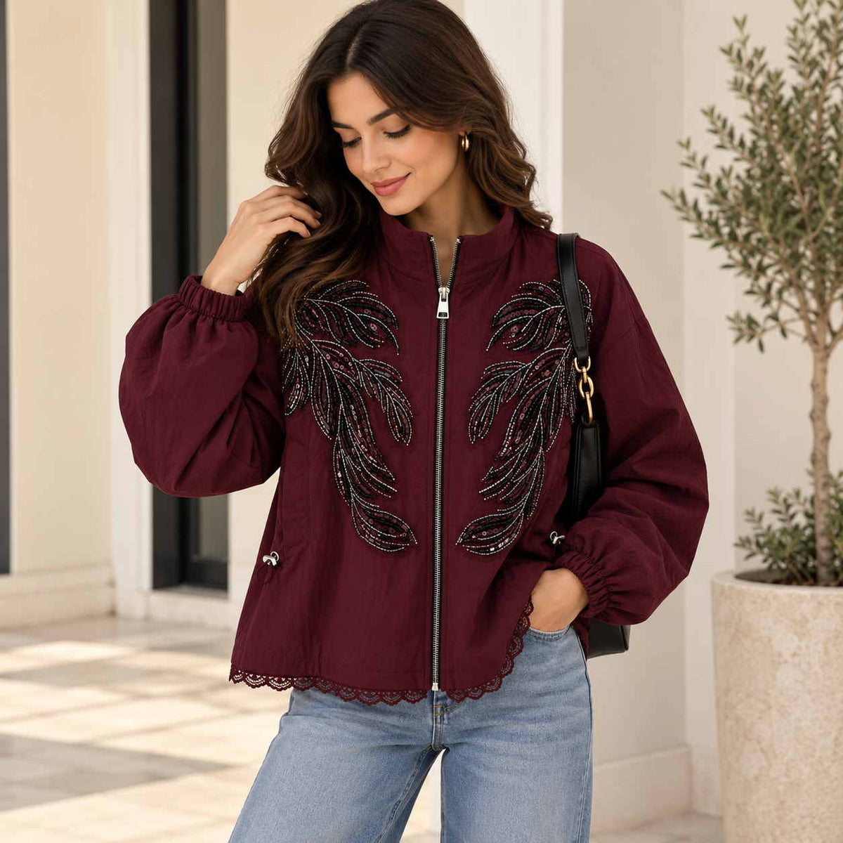 Woman in a burgundy zip jacket with black beaded leaf sprays, balloon sleeves and a lace trimmed hem