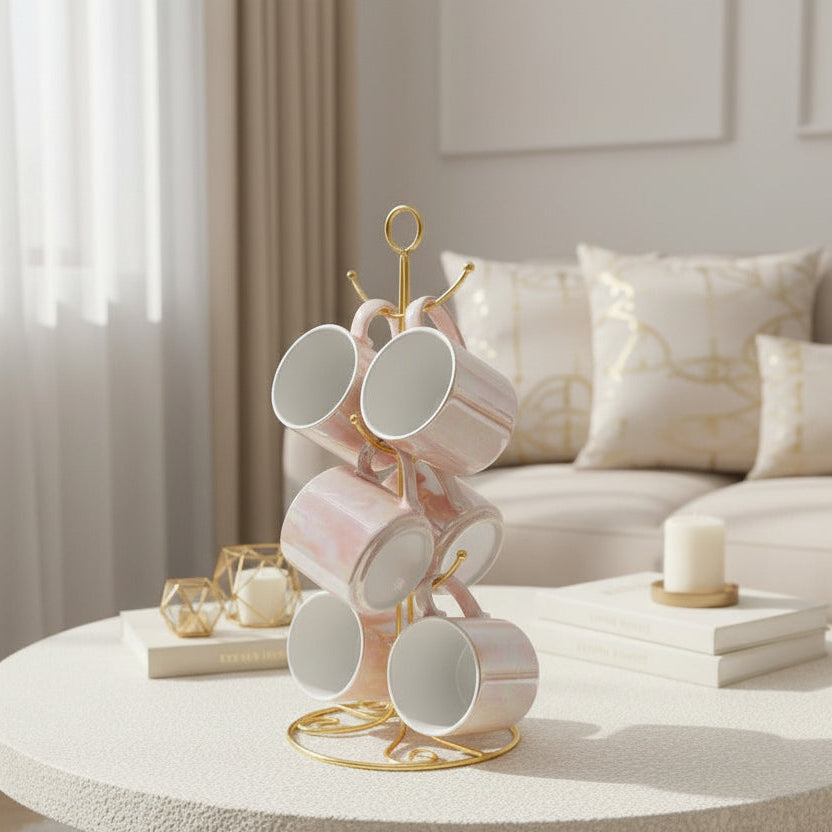 Six blush pink pearlescent mugs with gold rims hanging on a gold mug tree