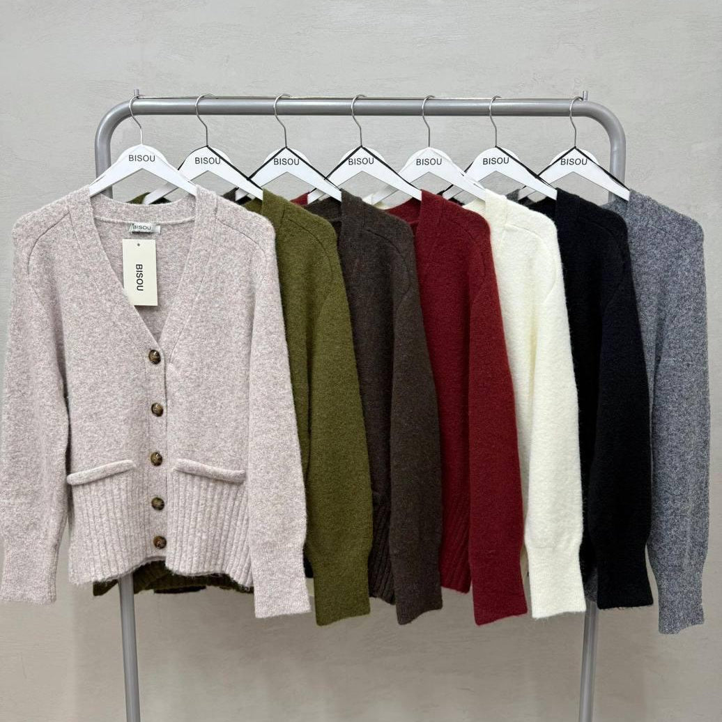 Button front knit cardigans on a rail, the beige one in front with its swing tag