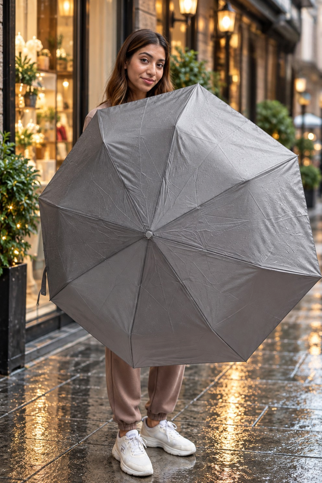 Woman on a rainy street holding open a plain grey folding umbrella
