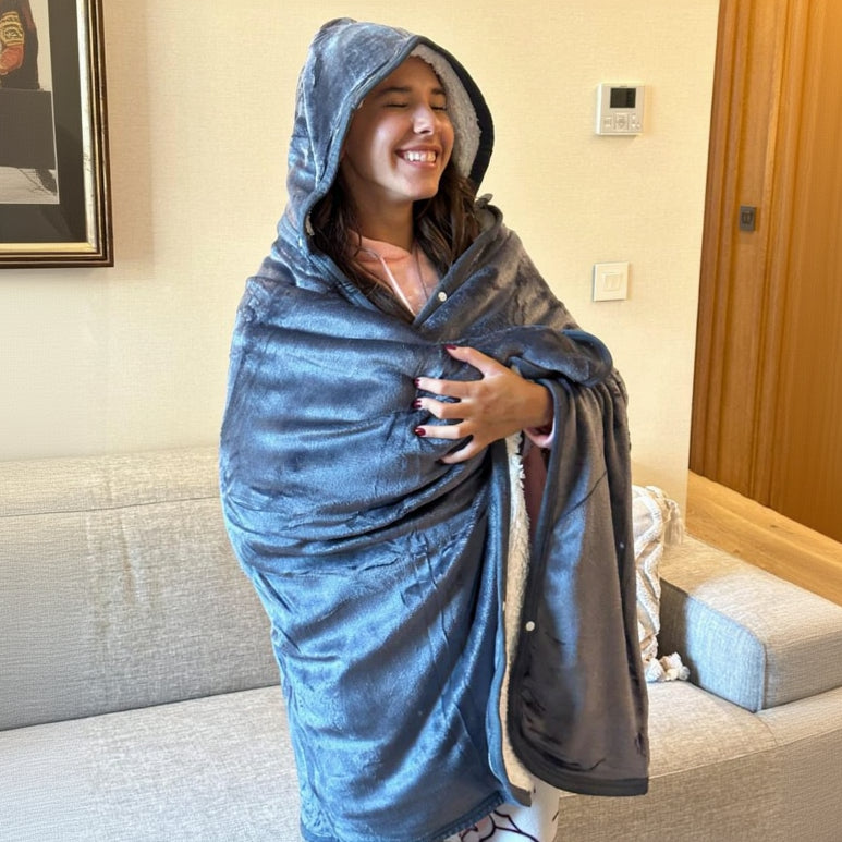 Person wrapped in a gray hooded blanket indoors