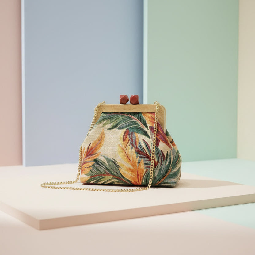 Tropical print handbag on a pastel backdrop with its gold chain laid out