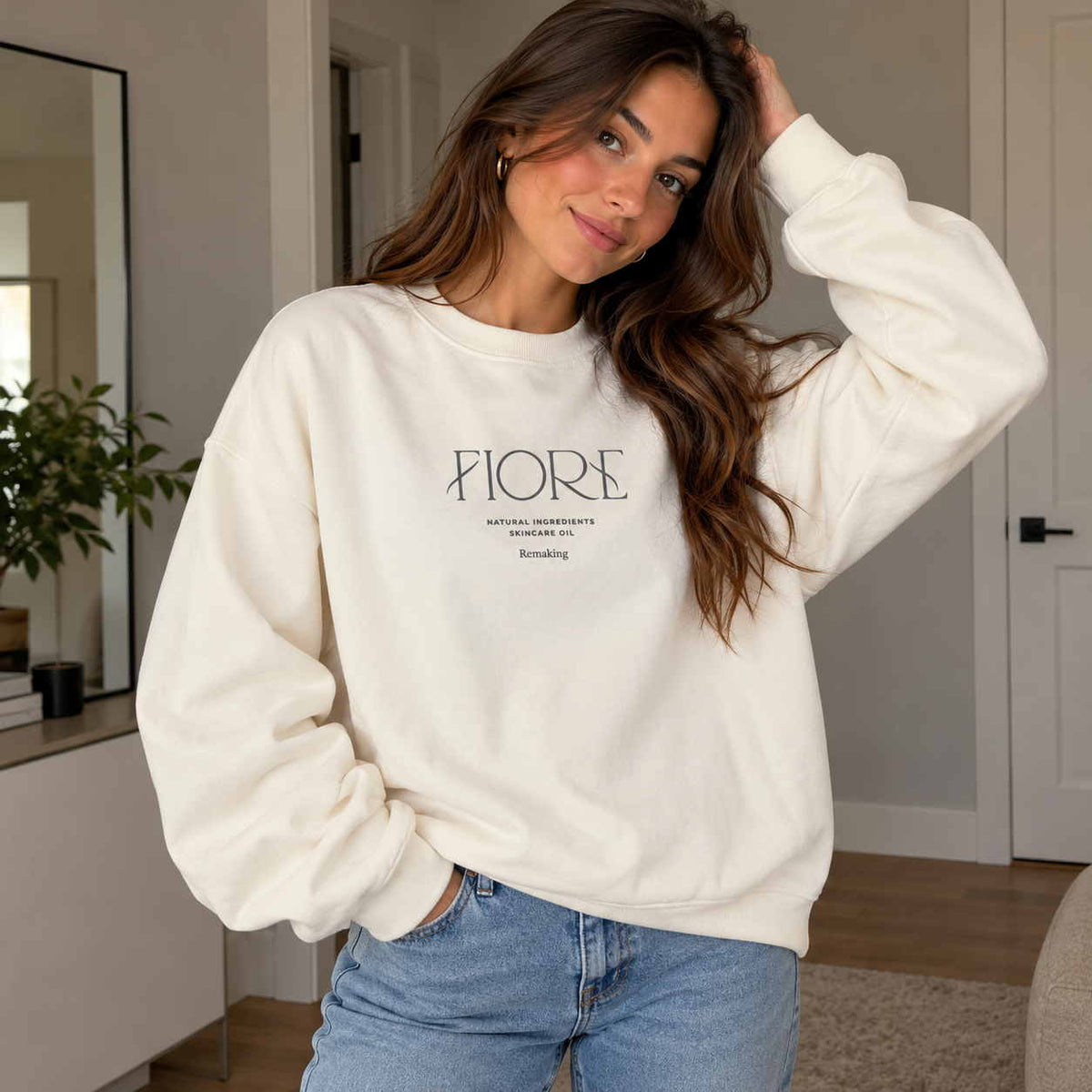 Woman in a cream crew neck sweatshirt with minimalist Fiore lettering, worn with light jeans