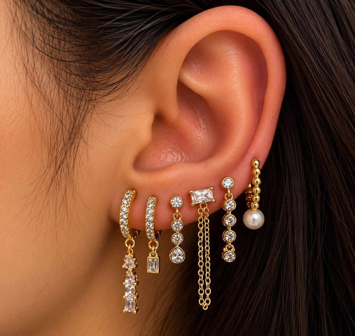 Ear stacked with gold crystal bezel drops, a baguette chain stud, pave huggies and a beaded pearl hoop