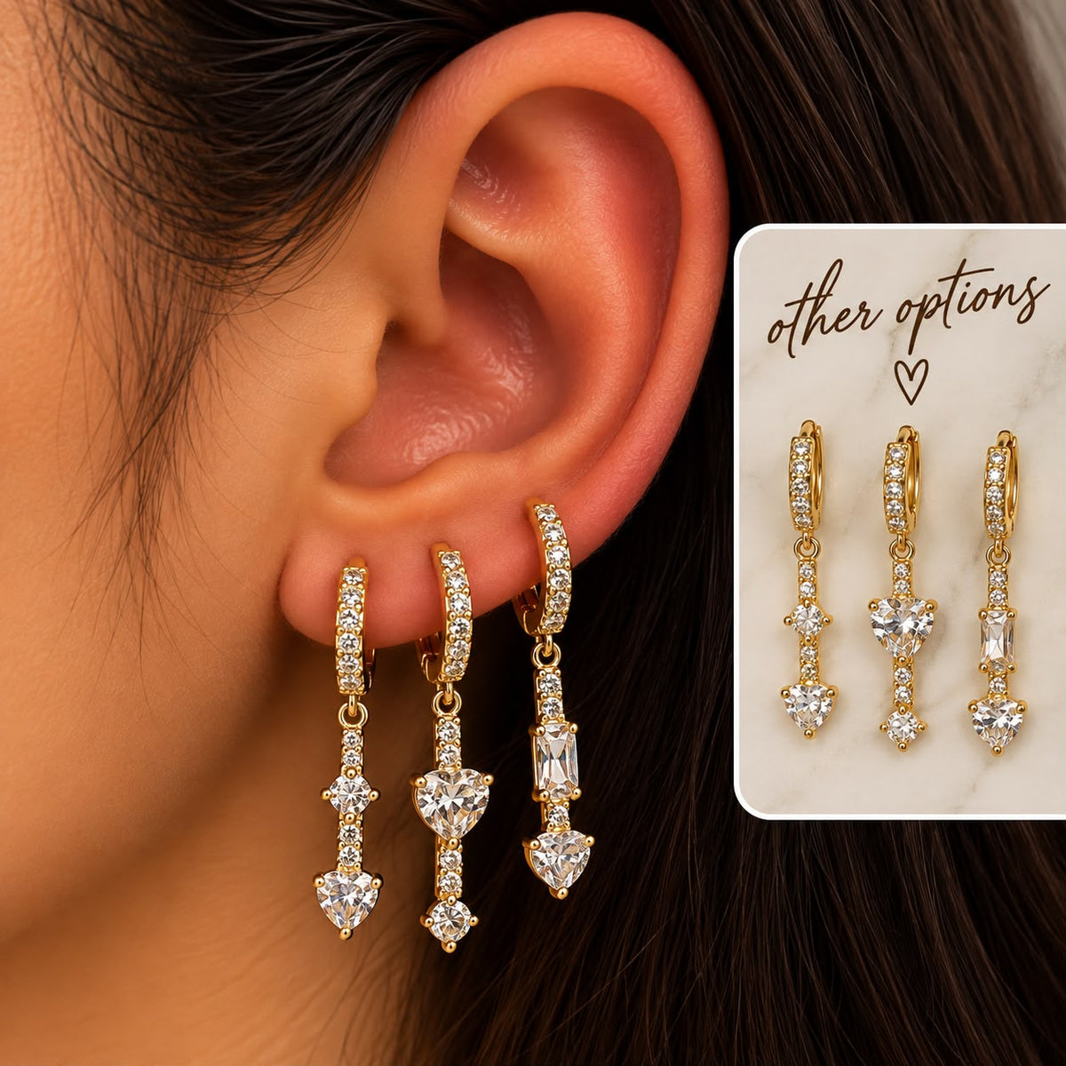 Ear wearing three gold pave huggies with long crystal drops ending in heart shaped stones