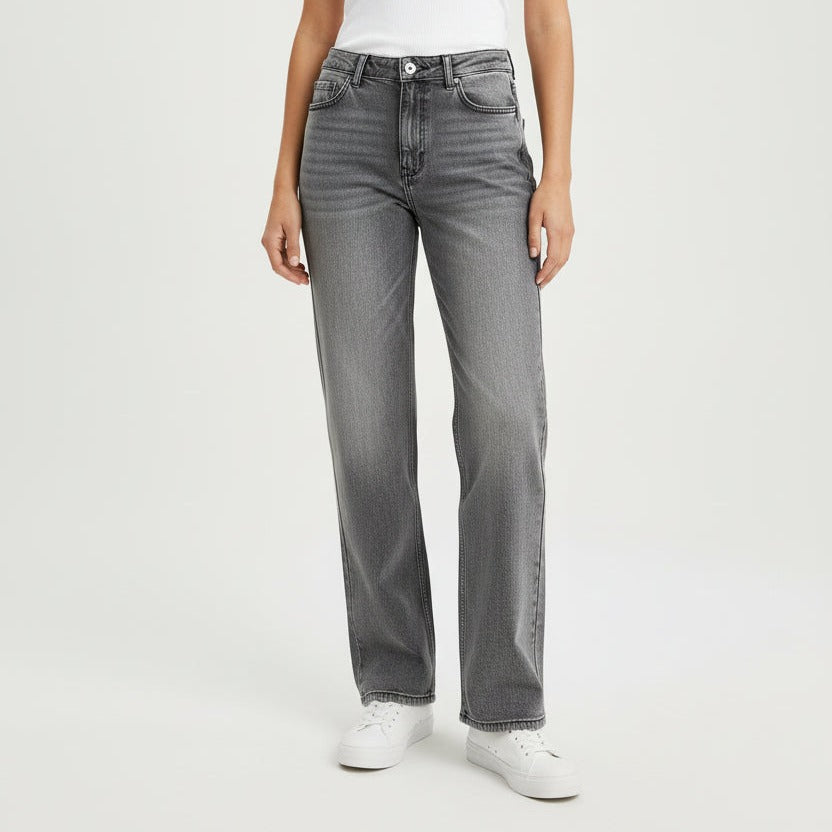 Person wearing dark gray jeans and white sneakers on a plain background