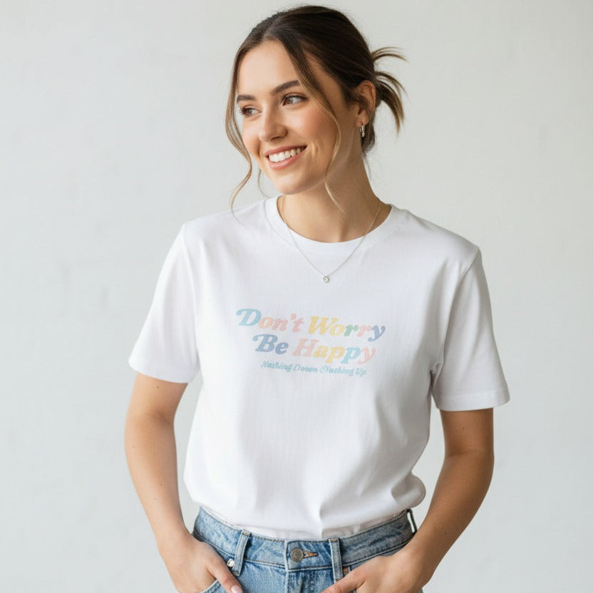 Woman wearing a white tshirt with colorful text and blue jeans against a plain background