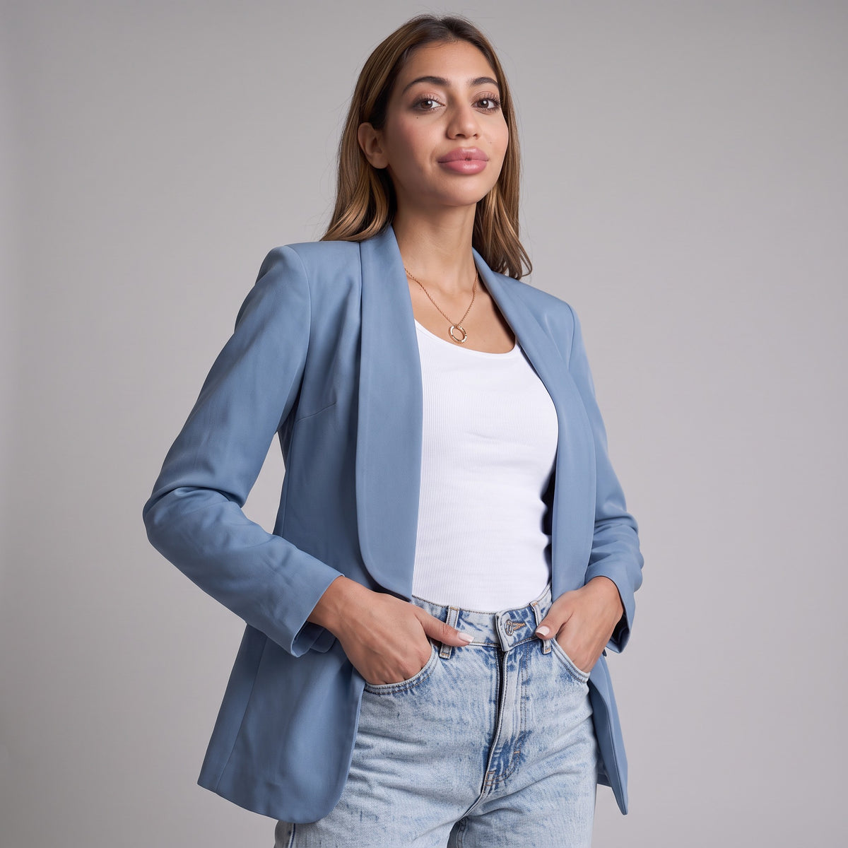Dusty blue shawl collar blazer worn open over a white top, hands in jean pockets