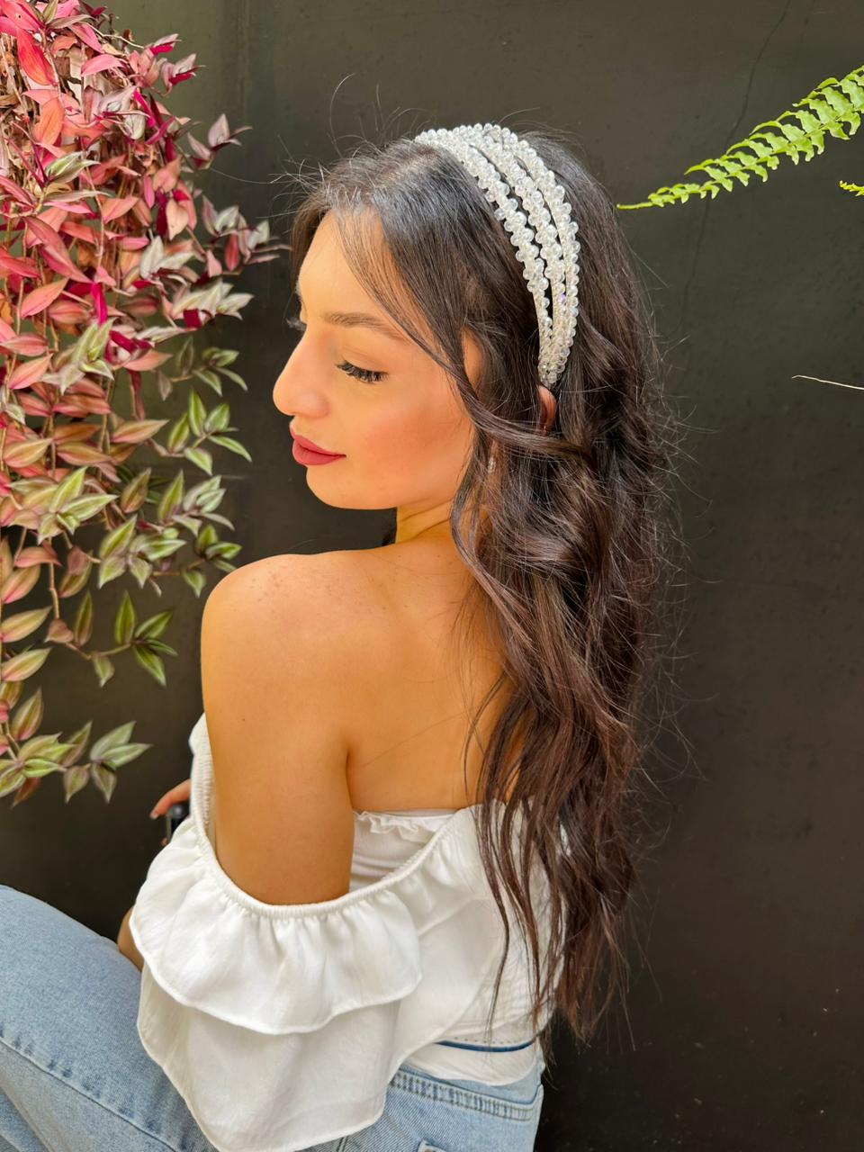 Woman wearing a white elegant bloom headpiece with plants in the background