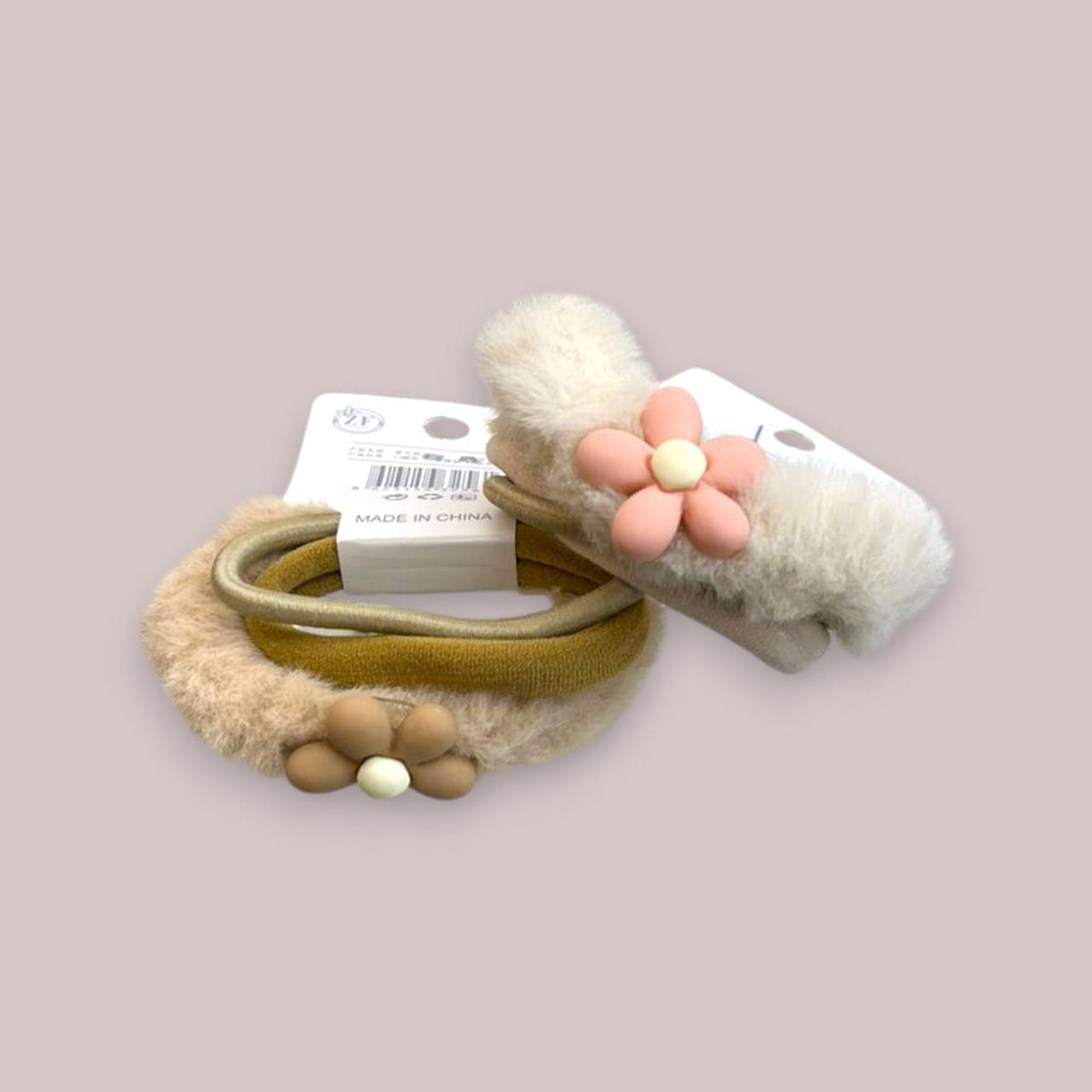 Two fluffy fur hair ties in beige and ivory with pink and brown daisy charms on stretch bands