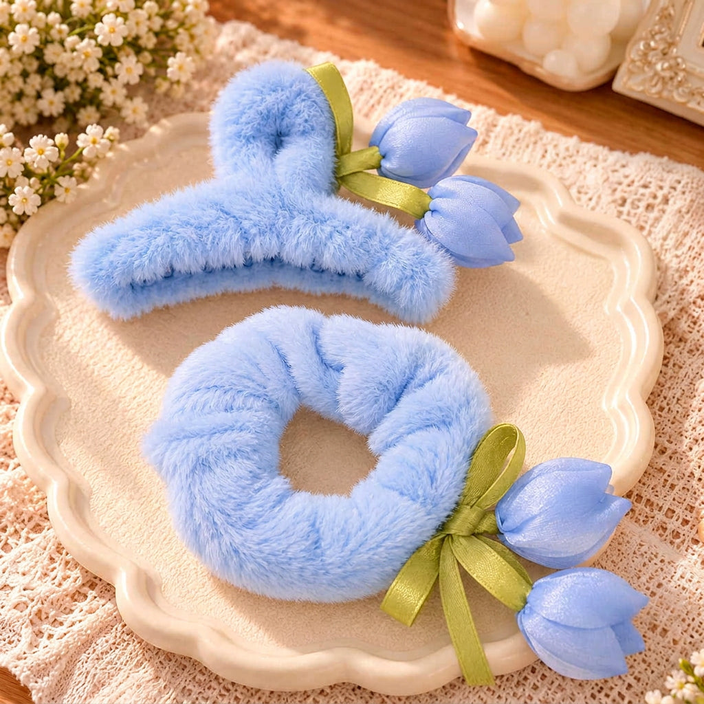 Blue fluffy claw clip and scrunchie with satin tulip buds and green ribbon on a cream dish