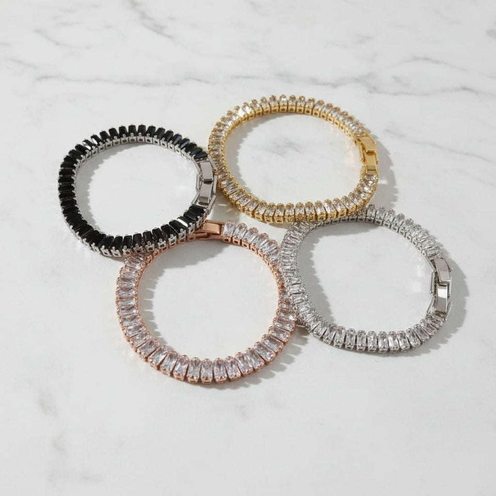 Four premium baguette tennis bracelets on a marble surface