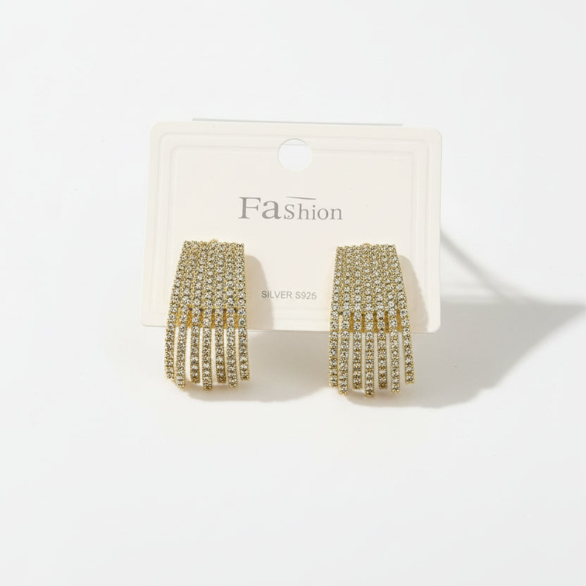 Gold fringe earrings on a 'Fashion' branded card against a beige background