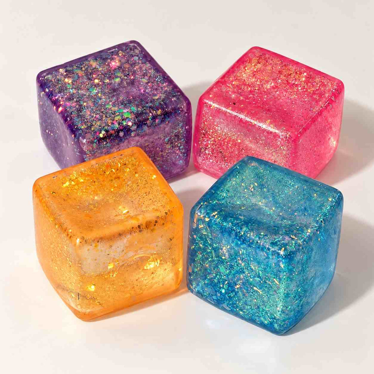 Four glitter jelly cube squishies in purple, pink, orange and blue