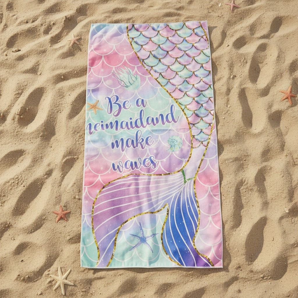 Pastel pink and mint beach towel with a gold outlined mermaid tail on sand