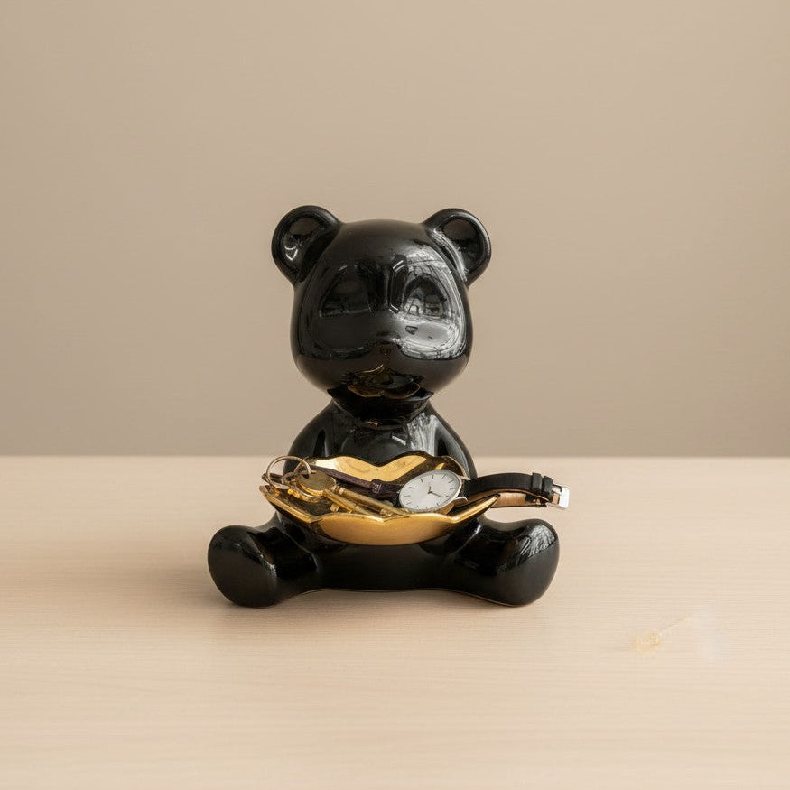 Black bear figurine holding a gold coin on a beige background