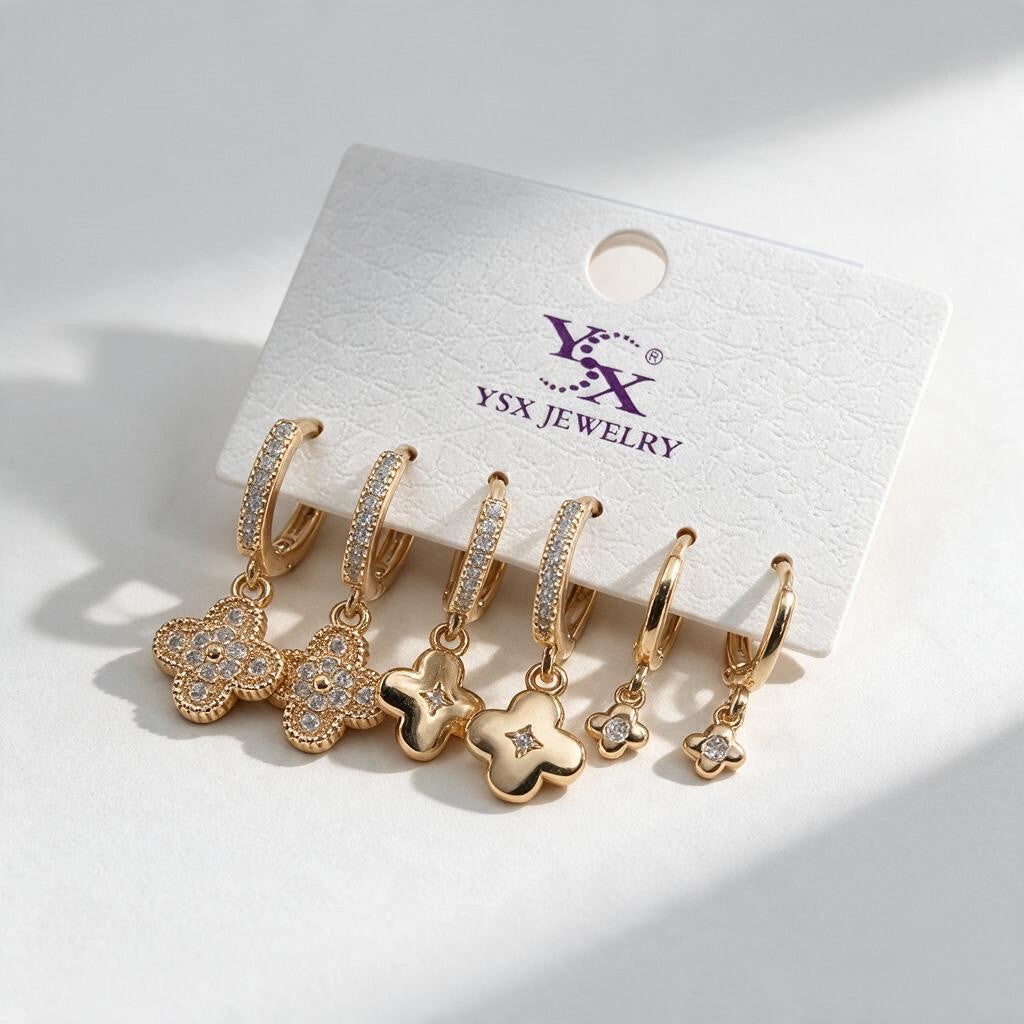 Three pairs of gold huggie earrings with pave, polished and mini clover drops on a display card